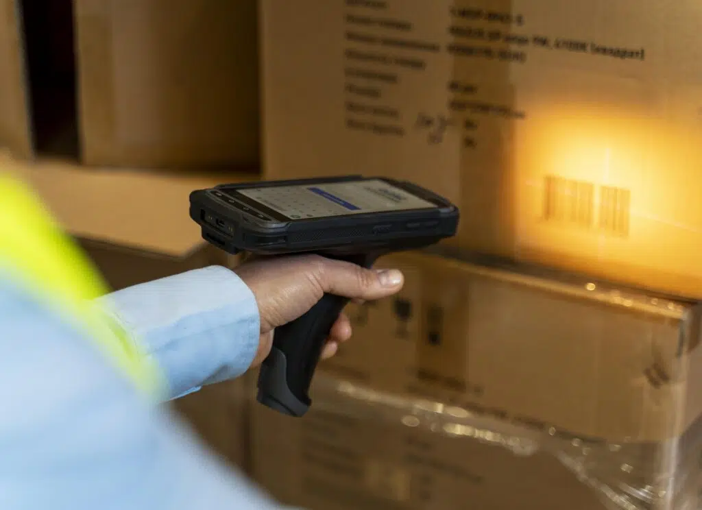 Pessoa usando sistema RFID para escanear uma caixa de papelão em um estoque.