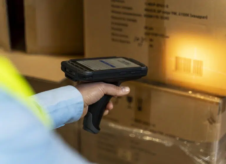 Pessoa usando sistema RFID para escanear uma caixa de papelão em um estoque.
